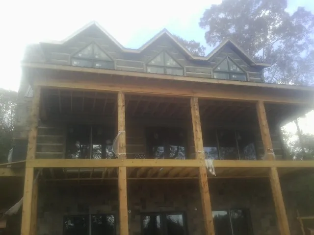 Dormers and porch framing on a large log home under construction — Roof Coating work by our crew in Clark