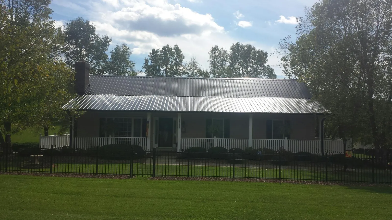 Gray metal roof on a brick ranch with a full width front porch — Gutter Guard Installation work by our crew in Clark