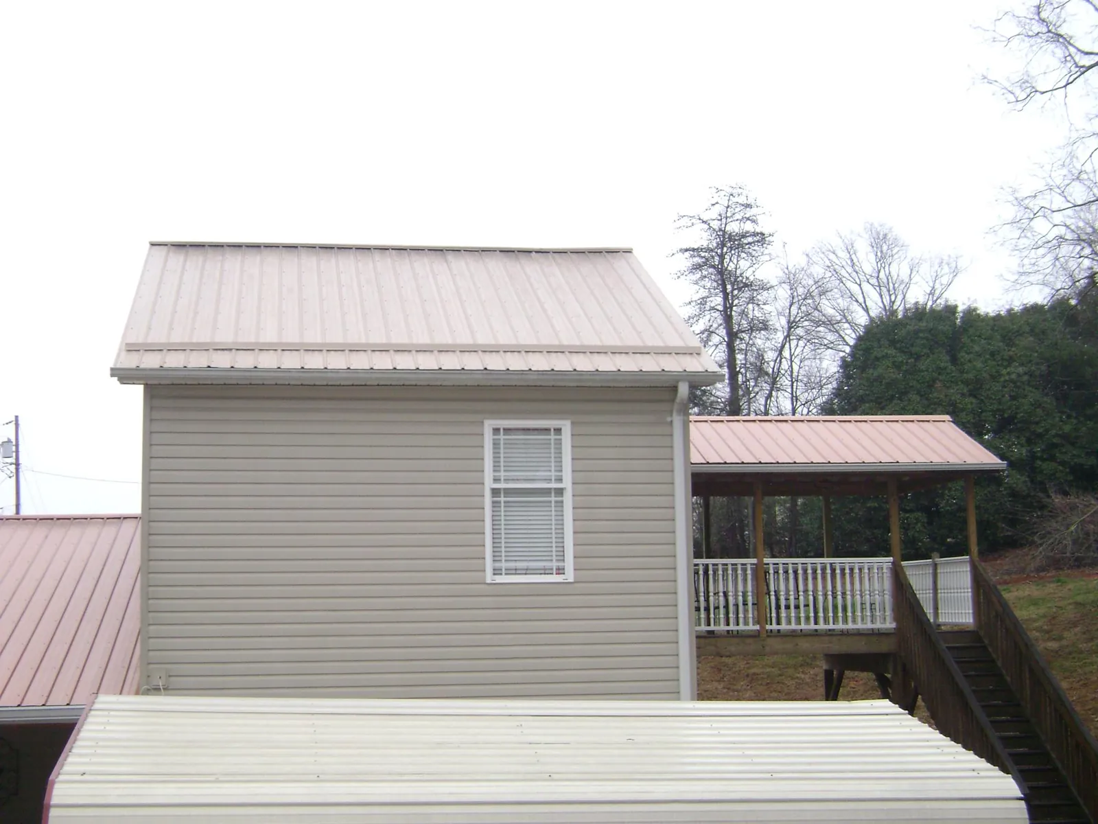 Tan metal roofs on a two story addition and attached porch, from a Roof Replacement job in Clark